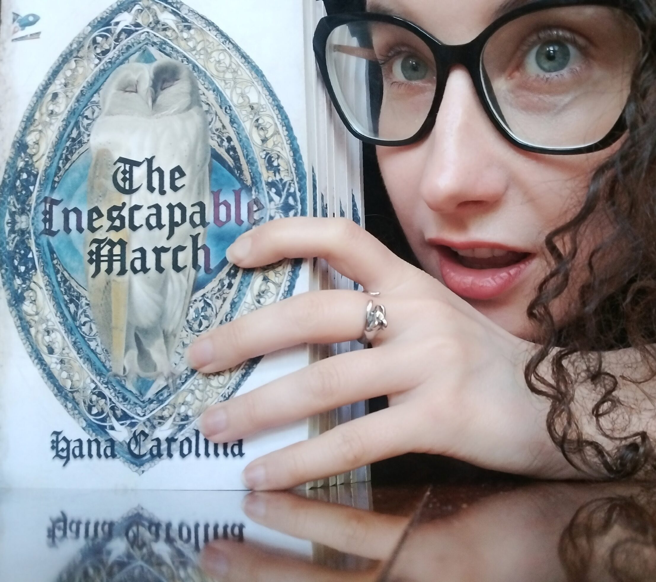 paperbacks of The Inescapable March on the left with Hana Carolina holding them on the right